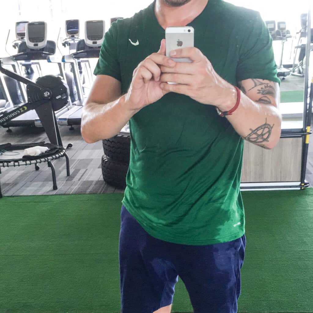 Mand tager selfie i fitnesscenter med løbebånd i baggrunden.