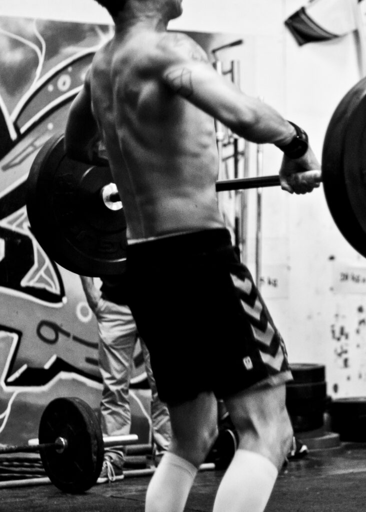 Person lifting a barbell in a black and white training facility.
